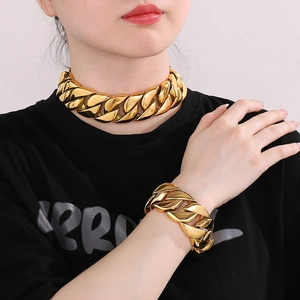 Detailed view of polished 31mm wide golden Cuban link necklace and bracelet on model