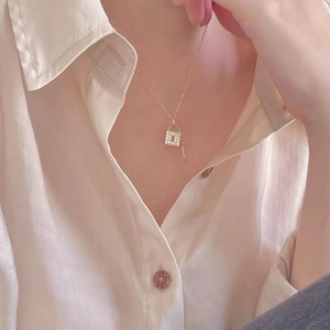 Detail of gold padlock and key necklace with crystal pavé on a model's neck