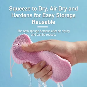 Pink 3D PVA bath sponge with scale texture being squeezed to show water absorption