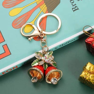 Christmas rhinestone bell keychain with red bells and green bow on a book background