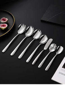 Polished 304 stainless steel cutlery set displayed on a dark marble surface with a book