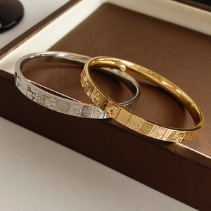 Detail of gold and silver polished metal bangles with mahjong pattern engraving