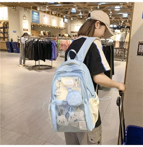 Detail of light blue school backpack with mesh pocket and round charm on shoulder strap