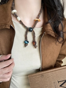 Close-up of bohemian woven cord necklace with amber and teal resin beads on a model