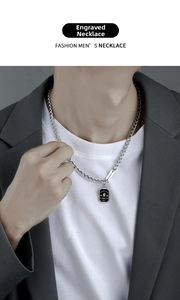 Close-up of silver Cuban chain necklace featuring black enamel good luck dog tag pendant