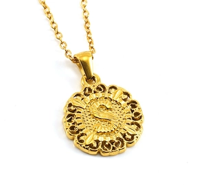 Detailed close-up of golden round pendant with hollow patterns and letter S engraving