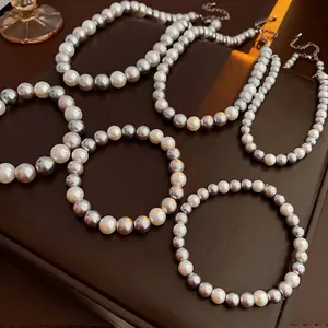 Elegant pearl jewelry set with grey and white pearls on a dark leather background