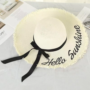 Detail of frayed edge straw hat with Hello Sunshine embroidery and black ribbon bow