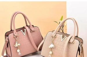 Detail of pink and apricot crocodile embossed leather bags with elegant gold V buckles