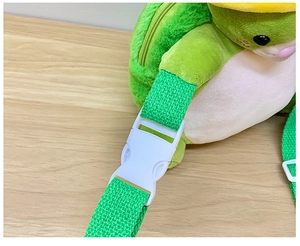 Close-up of adjustable green strap and white plastic buckle on the plush crossbody bag