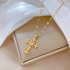 Elegant gold cross necklace with pave zircons on champagne jewelry box display