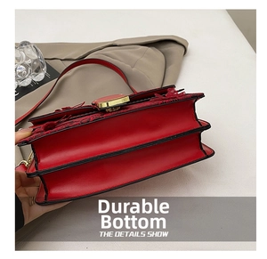 Detail view of the red crossbody bag with dual-layer bottom and gold metal clasp closure