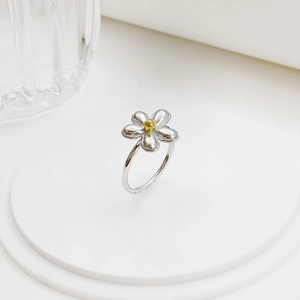 Minimalist daisy flower ring in silver and gold stainless steel on a white podium
