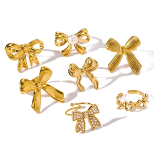 Gold stainless steel bow ring set with pearls and zircon stones on white background