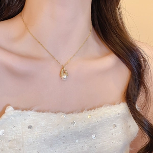 Detail einer 18k vergoldeten Kette mit Zirkon-Hufeisen und Perle am Hals der Frau