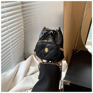 Close-up of black quilted bucket bag with golden camellia charm and chain strap