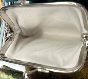 Detail of silver metal clasp closure and white woven lining of the unicorn coin purse