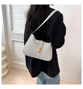 Chic cream-colored underarm bag worn on shoulder by model in elegant black blazer