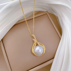 Detail of gold necklace featuring teardrop pendant with large pearl and sparkling diamonds