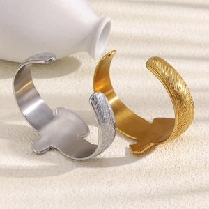 Gros plan sur la texture de plume d'oiseau dorée et argentée du bracelet en acier