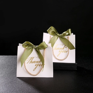 Detailed view of white paper gift bags with olive green ribbons and gold Thank you text