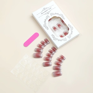 Detail of red cat eye gradient press-on nails with glitter, glue tabs, and pink file
