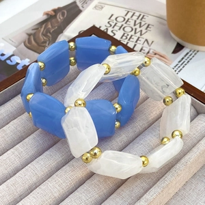 Makro-Detail von blau-marmorierten Harzarmbändern mit goldenen Metall-Trennperlen