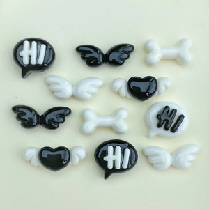 Detaillierte Draufsicht auf schwarz-weiße Harzflügel, Knochen und Herz-Zubehör für DIY-Handwerk