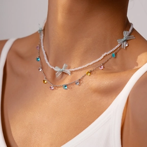 Detail of double-layer stainless steel necklace with blue mesh bows and colorful zircons