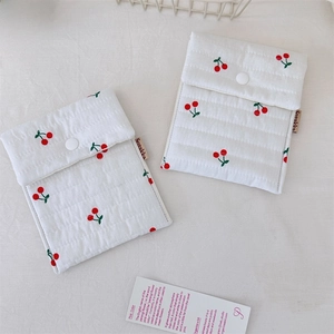 Detail of white quilted cotton toiletry bags featuring a cute red cherry print and snaps