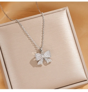 Détail du collier à nœud en argent serti de zircons sur un support luxueux en soie champagne