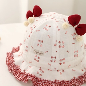 Vue détaillée d'un chapeau bébé à cerises avec nœuds rouges et bords à volants