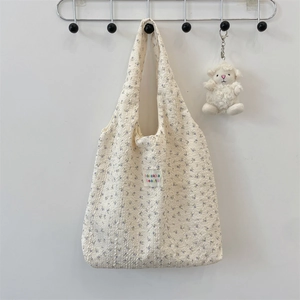 Detail of beige floral puffy tote bag with embossed bear texture and plush sheep charm