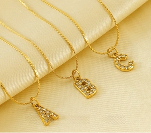 Dettaglio dei ciondoli con lettere A, B, C in acciaio inossidabile dorato con strass