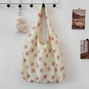 Detail of floral embroidery on a beige canvas tote bag with pink flowers