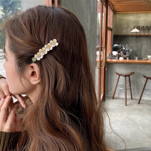 Elegant white enamel cherry blossom hair clip with pearls and green leaf on hair
