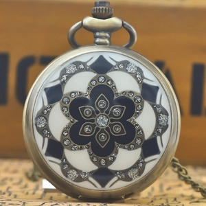 Vintage bronze quartz pocket watch with floral geometric patterns on a wooden background