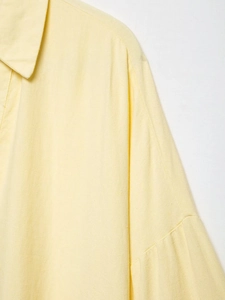 Detail of light yellow linen blend shirt showing the textured collar and shoulder fabric