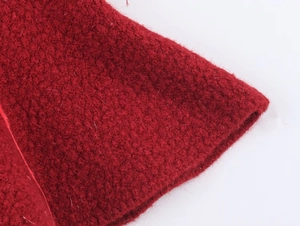 Macro shot of deep red bouclé knit fabric texture showing high quality wool fibers