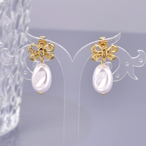 Detailed view of gold bow earrings with cubic zirconia and large oval pearls