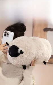 Gros plan d'un oreiller en peluche mouton blanc doux avec visage noir dans les bras