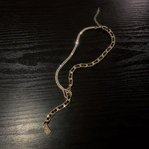 Détail du collier chaîne dorée avec ruban noir tressé et accents de strass brillants