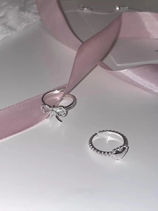 Detail of silver S925 heart ring and bow ring with pink ribbon and lace decoration