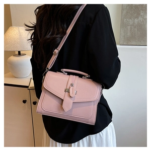 Detailed view of pink textured leather crossbody bag with top handle and metal buckle