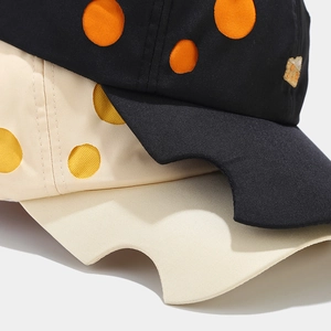Detail of unique cheese-shaped cutout brim and polka dot embroidery on baseball caps