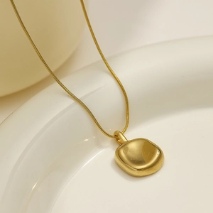 Macro view of gold irregular geometric pendant on a sleek snake chain necklace