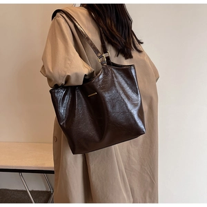 Close-up of high-quality brown faux leather tote bag texture and slim shoulder straps