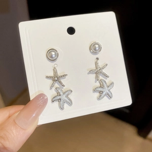 Detail of silver starfish earrings with white enamel and pearls for beach vacation
