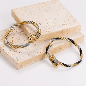 Trendy stainless steel cable twisted bangle in gold and silver finish on stone pedestals