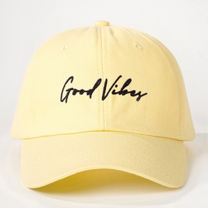 Close-up of black Good Vibes embroidery on a light yellow cotton canvas baseball cap